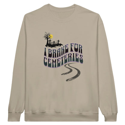 Gildan 18000 Crewneck Sweatshirt with the words I Brake For Cemeteries in black and grey with purples shading accents.. There are skid marks under the words and a small graveyard graphic to the top left of the words. The sweatshirt is sand