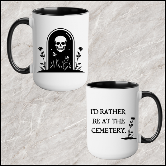 15 oz white ceramic mug with a black handle and black interior. One side says Id rather be at the cemetery the otherside has a tombstone with a skull on it