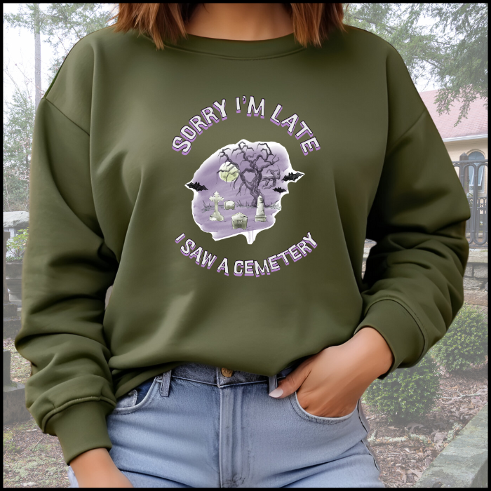 Gildan 18000 Crewneck Sweatshirt with the words Sorry I'm Late I saw a cemetery around a graphic of a cemetery.  Colors of the graphic are purple and grey. Sweatshirt is military green.